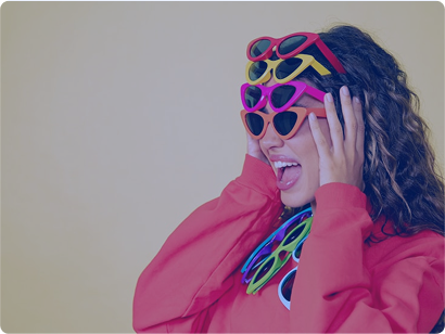 Person with curly dark hair wearing pink top and colorful sunglasses